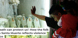 A devotee carrying his daughter rests his hand on the glass to an altar to La Santa Muerte in Tepito in Mexico City. AP Photo/Rebecca Blackwell